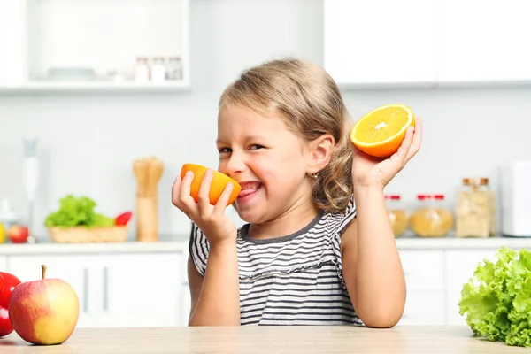 Dziewczynka z pomarańczy, siedząc w kuchni — Zdjęcie stockowe