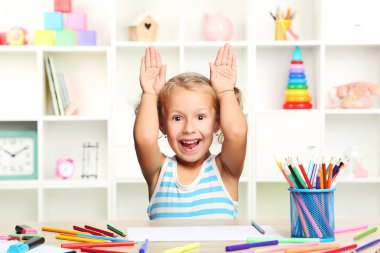 Oturma ve masada çizim küçük kız