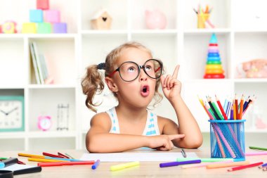 Oturma ve masada çizim küçük kız