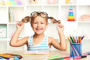 Oturma ve masada çizim küçük kız