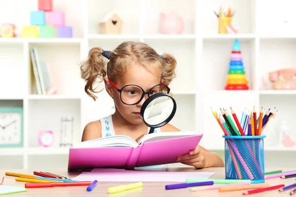 Menina sentada com livro na mesa — Fotografia de Stock