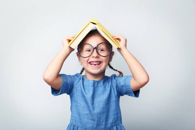 Gözlük ve gri arka plan üzerinde kitap ile küçük kız portresi