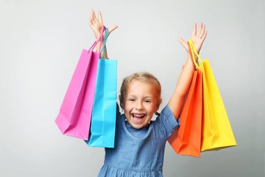 Küçük kız alışveriş torbaları gri arka plan üzerinde tutarak portresi