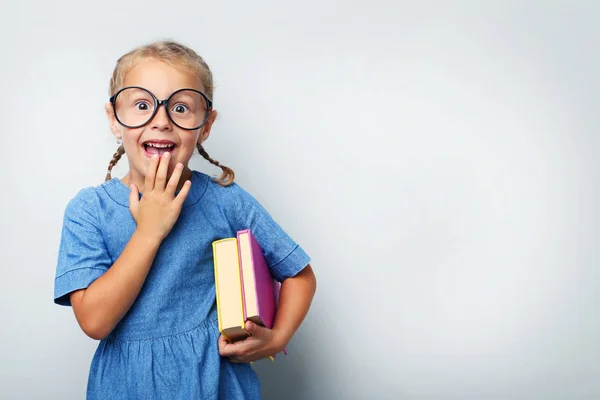 Retrato de menina com óculos e livros em fundo cinza — Fotografia de Stock