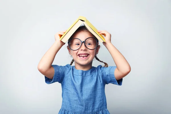 Retrato de menina com óculos e livro sobre fundo cinza — Fotografia de Stock