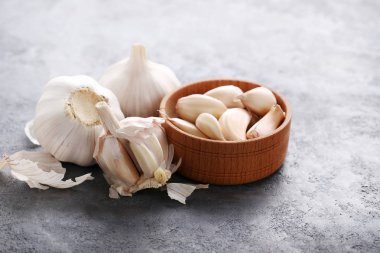 Gri ahşap masa üzerinde bir kapta sarımsak