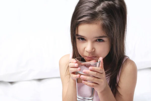 美丽的小女孩饮用水在白色的床上 — 图库照片