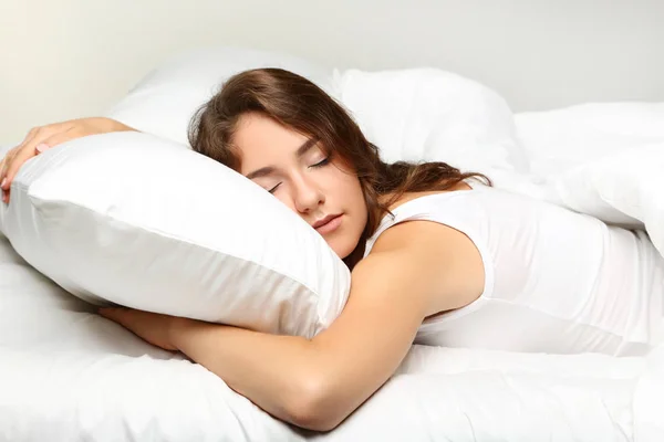 Junge Frau schläft im weißen Bett — Stockfoto