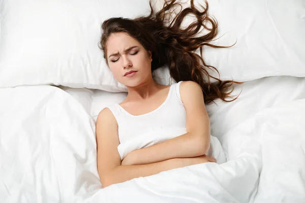 Wanita muda sakit berbaring di tempat tidur putih — Stok Foto