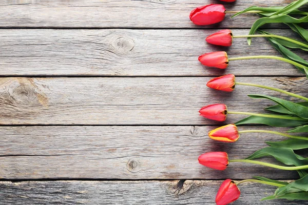 Red tulips on grey wooden table — Stock Photo, Image