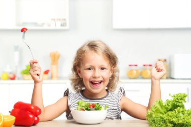 Küçük kız mutfakta salata yemek
