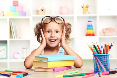Kitaplar masada oturan küçük kız