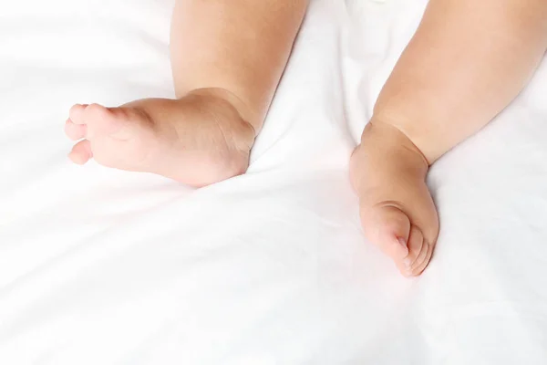 Nyfödd baby fötter på vit säng — Stockfoto