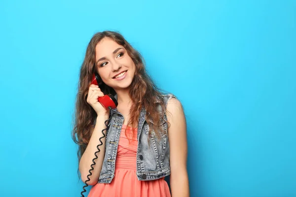 Portret van een jonge vrouw met rode telefoon op blauwe achtergrond — Stockfoto