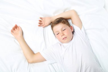 Beyaz yatakta uyuyan genç çocuk