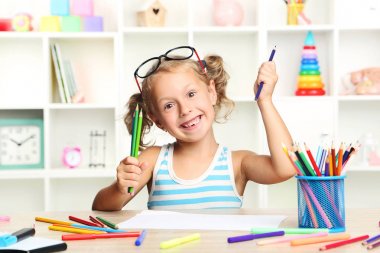 Oturma ve masada çizim küçük kız