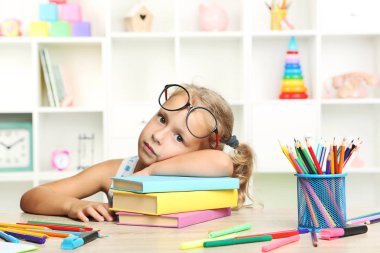 Kitaplar masada oturan küçük kız