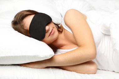 Genç kadın eyemask beyaz yatakta yatıyor
