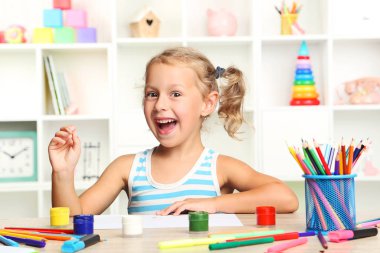 Oturma ve masada çizim küçük kız