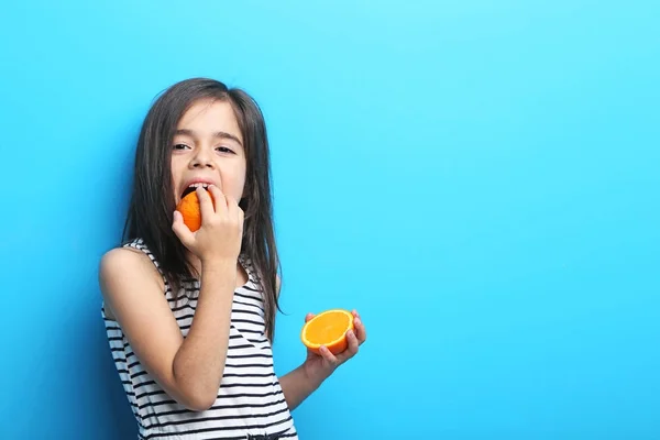 Menina bonita com laranja no fundo azul — Fotografia de Stock