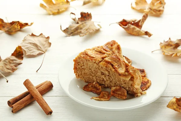 Slice of apple cake in plate on white wooden table — Stock Photo, Image