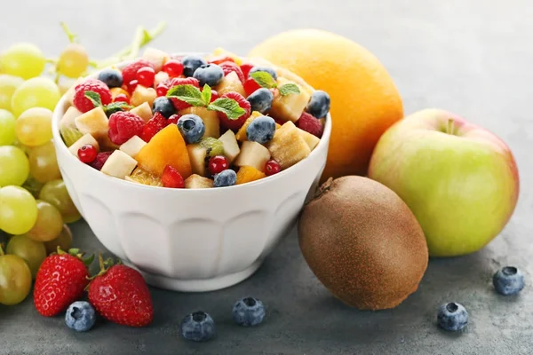 Färsk fruktsallad i skål på grå träbord — Stockfoto