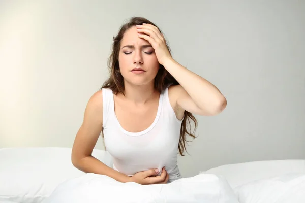 Mujer joven enferma acostada en la cama blanca — Foto de Stock