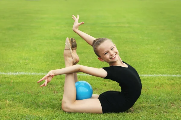 Yeşil çimenlerin üzerinde topu ile genç kız jimnastikçi