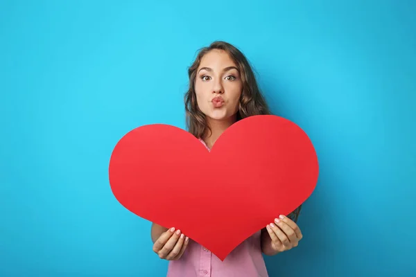 Портрет молодой женщины с красным сердцем на синем фоне — стоковое фото