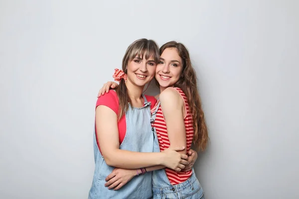 Two young woman hugging each other on grey background — Stock Photo, Image