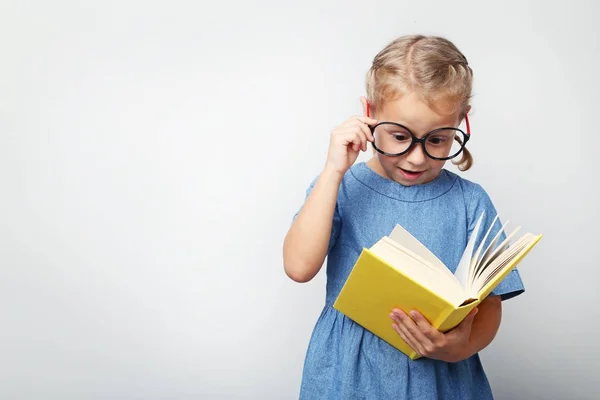 Retrato de menina com óculos e livro sobre fundo cinza — Fotografia de Stock