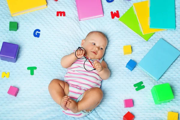 Novorozené miminko s knihami a písmena na posteli — Stock fotografie
