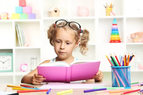 Маленька дівчинка сидить з книгою за столом — стокове фото