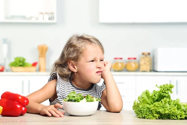 Menina comendo salada na cozinha — Fotografia de Stock