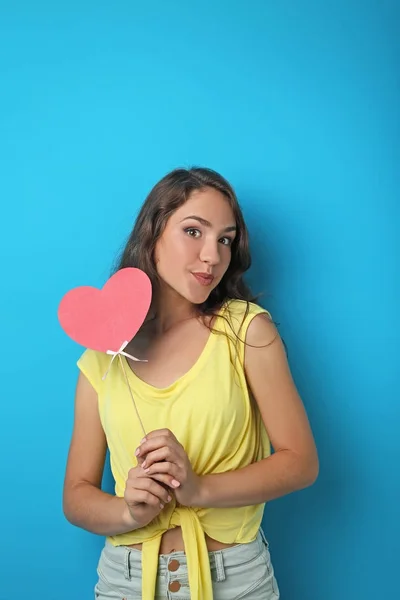 Retrato de mujer joven sosteniendo el corazón rosa sobre fondo azul —  Fotos de Stock