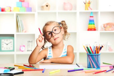 Oturma ve masada çizim küçük kız