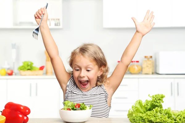 Niña comiendo ensalada en la cocina — Foto de Stock