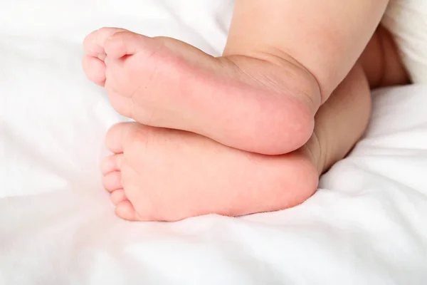 Pés de bebê recém-nascidos na cama branca — Fotografia de Stock