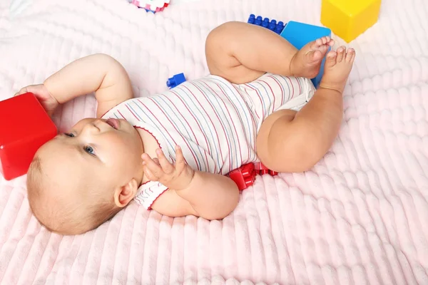 Bayi kecil yang baru lahir dengan mainan di tempat tidur merah muda — Stok Foto