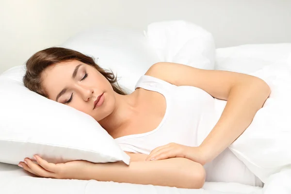 Mujer joven durmiendo en cama blanca — Foto de Stock