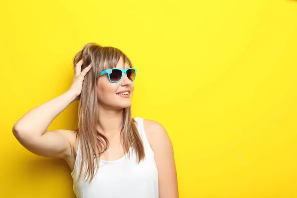 Portrét mladé ženy se slunečními brýlemi na žlutém podkladu — Stock fotografie