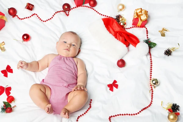 Novorozené miminko s vánoční výzdobou na bílé posteli — Stock fotografie