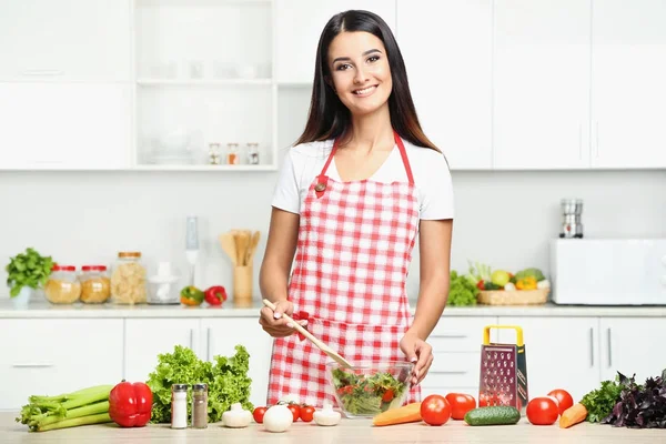 Bella giovane donna che cucina insalata in cucina — Foto Stock