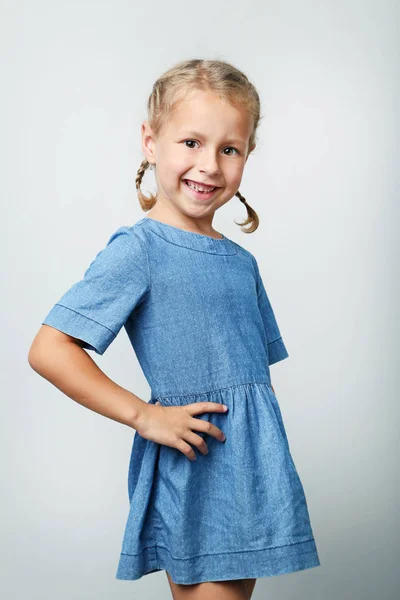 Портрет маленької дівчинки в синій сукні на сірому фоні — стокове фото