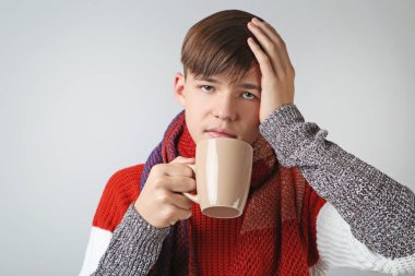 Gri arka plan üzerinde çay ile genç hasta çocuk