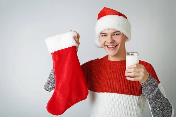 Young boy in santa hat holding christmas sock and glass of milk — Stock Photo, Image