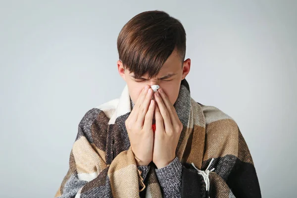 Kleiner kranker Junge mit Taschentuch auf grauem Hintergrund — Stockfoto