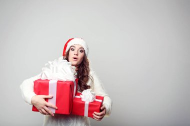 Noel Baba şapkası ile hediye kutuları gri arka plan üzerinde genç kadın