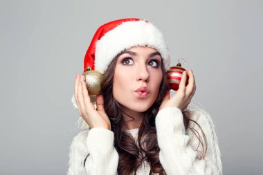 Noel Baba şapkası gri arka plan üzerinde baubles ile genç kadın