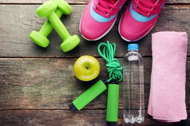 Pembe şişe, yeşil elma, halter ve ahşap masa atlama ipi